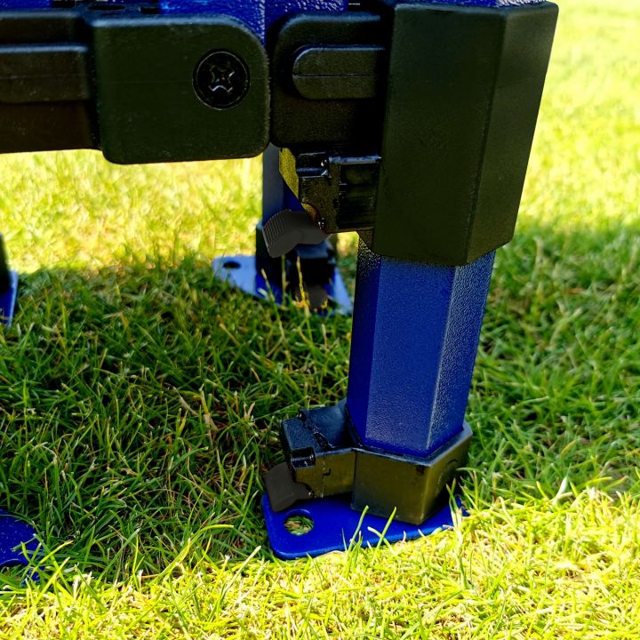 Detalje af den nederste del af det blå teltben med den blå fod og den sorte skydemekanisme, der står på græsset.