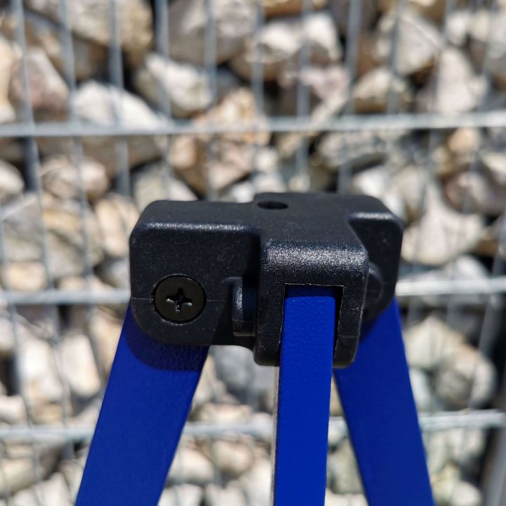 Detalje af den sorte plastforbindelsesdel (øverste del af benet) på den blå teltkonstruktion, med en baggrund lavet af grå småsten/grus